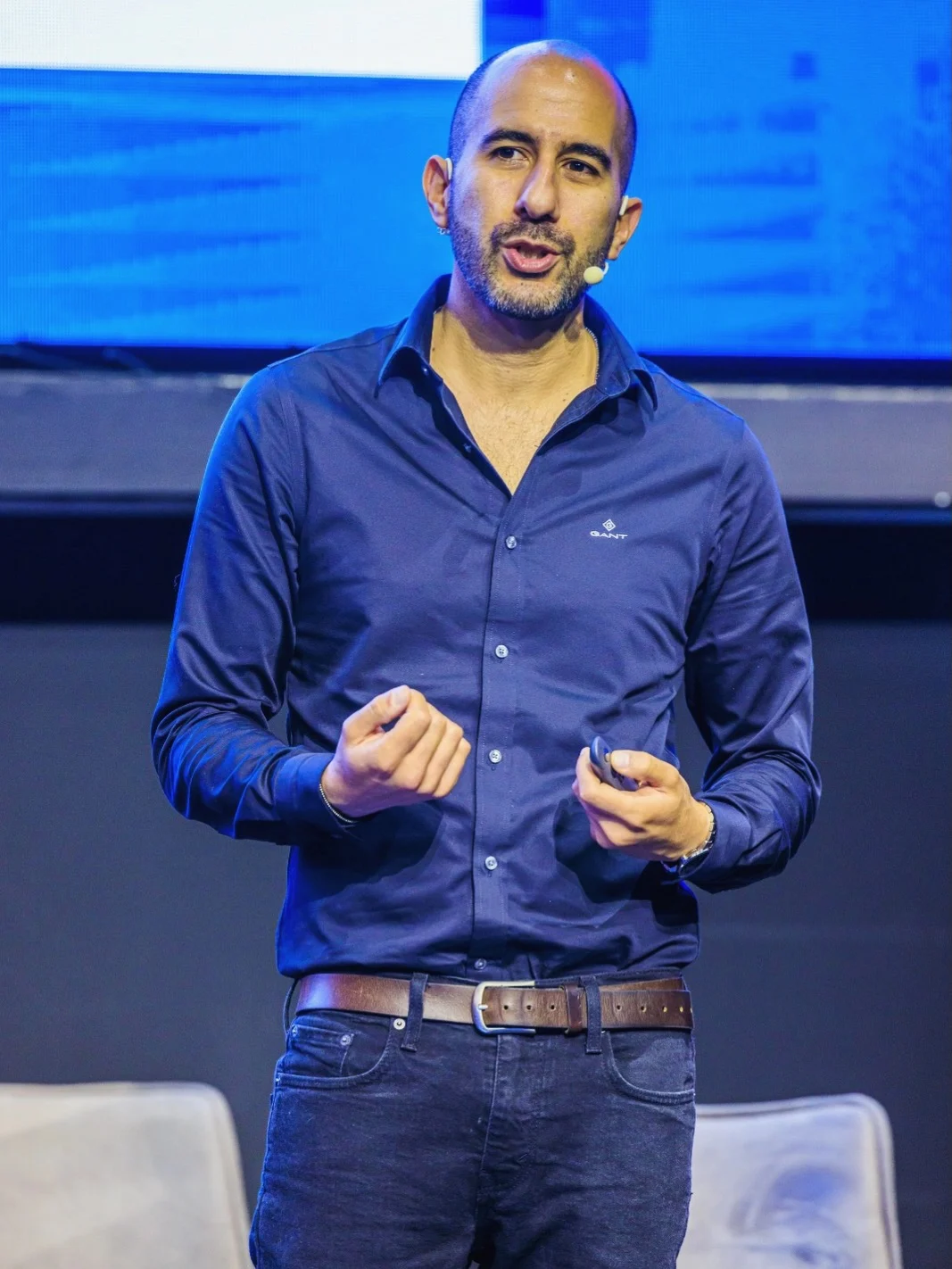 Haviv Ohayon speaking on stage with a headset microphone.